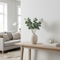 Six realistic faux eucalyptus stems in ceramic vase on console table in bright Scandinavian living room