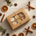 Three small soy candles in kraft gift box tied with twine, surrounded by dried orange slices and cinnamon sticks